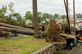 The street sign for 102 Hamilton Oaks lies on its side amid a pile of storm debris on Wednesday. (The Sentinel-Record/James Leigh)